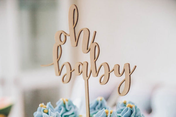 a cut out baby shower sign on top of a cake
