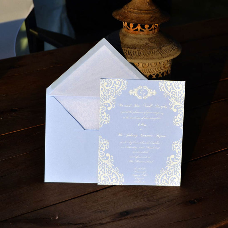 The Merrion wedding invitations contrasting with dark wooden table and lamp 