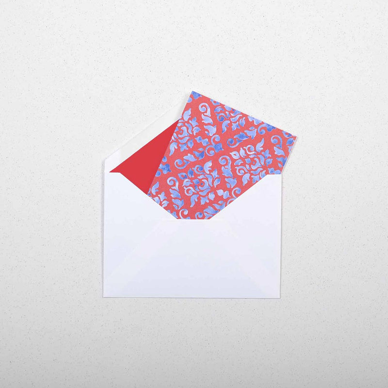 the blue and red damask pattern greeting card shown in it's white envelope which are lined in bright red tissue paper