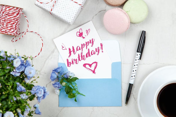 A birthday card, showing the phrase happy birthday, in a blue envelope 