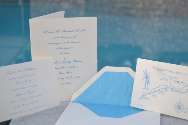 Light blue wedding ink on handmade cream cards with a pool in the background