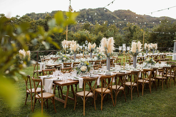 A table setting for a rustic wedding, showing a floral arrangement on the wooden tables