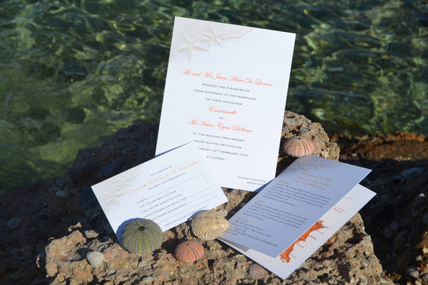 Wedding stationery with a seashell design pictured on a rock by the sea