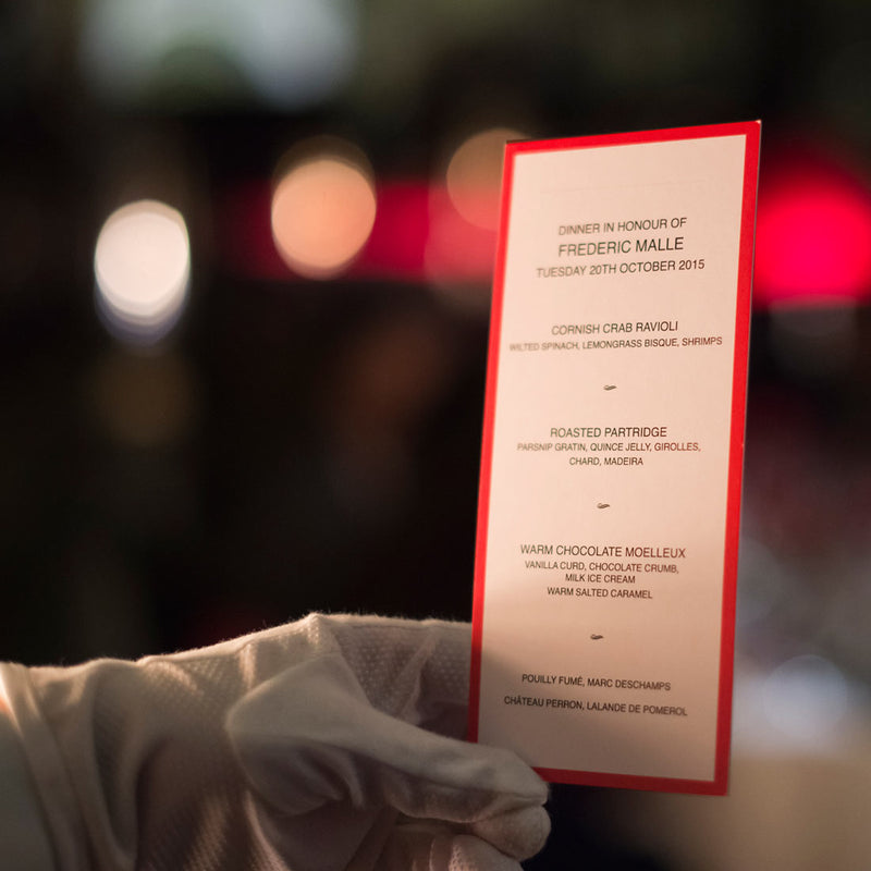 The Burlington menu held by a gloved hand from side on, showing the red border contrasting with the black text