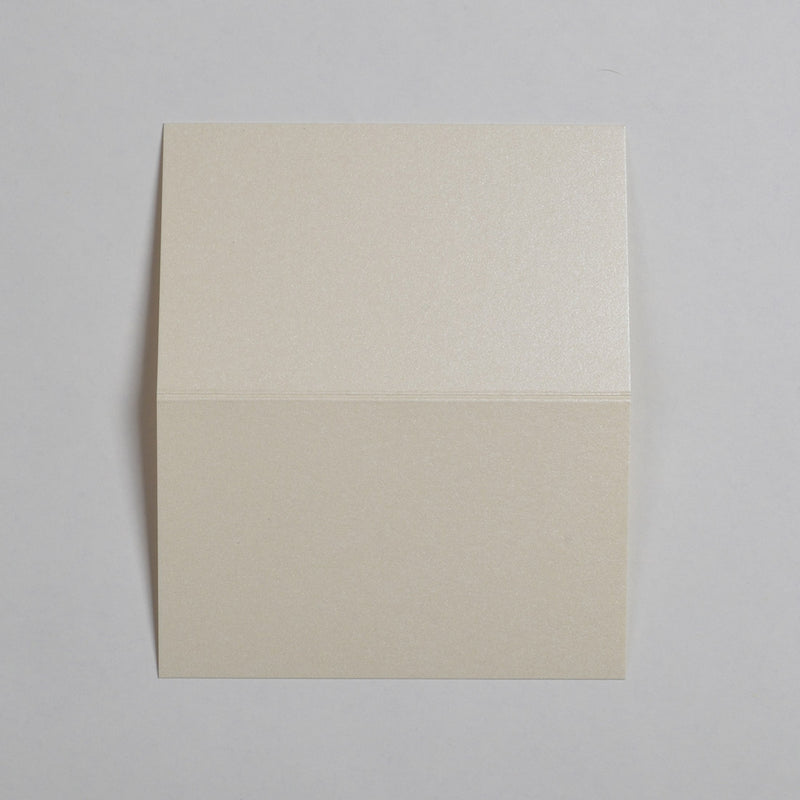 The Candlelight Cream Wedding name place cards shown flat on a table surface with the crease in the middle