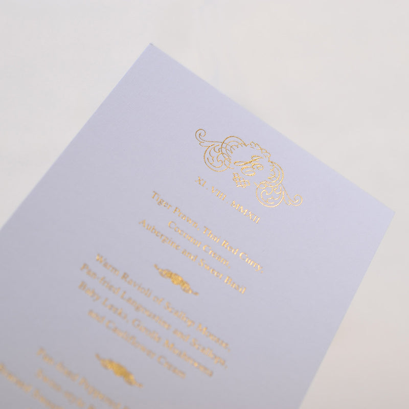 The light bounces off the gold foiled monogram and elaborate frame at the head of the Cologne wedding menu cards