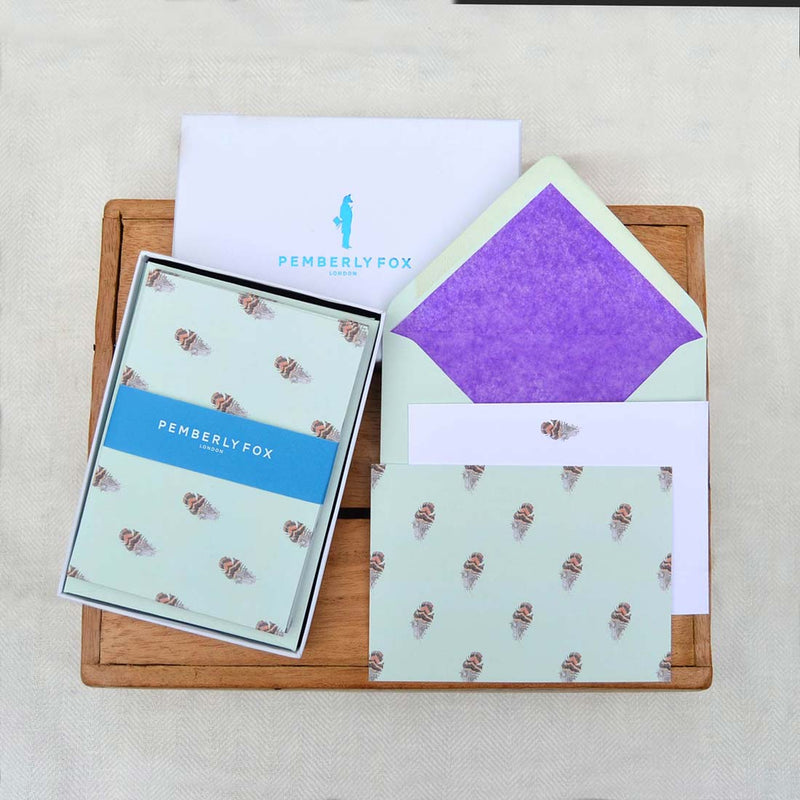 A grouse feather pattern presented on a mint green base, with matching green envelopes and purple tissue paper lining