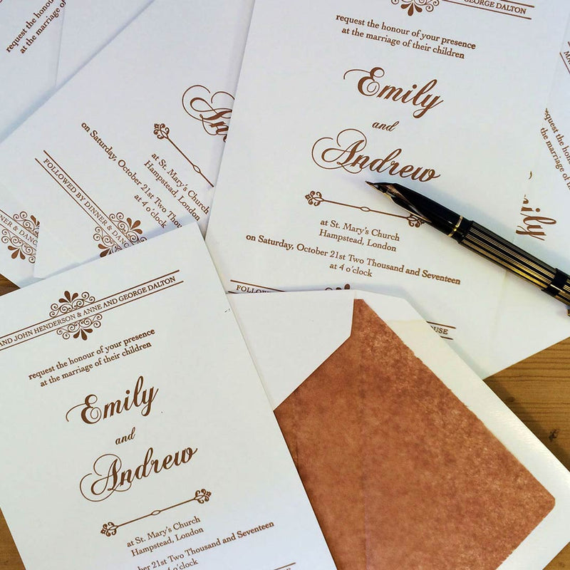 The kenwood letterpressed wedding invitations in a pile on the table with a fountain pen             