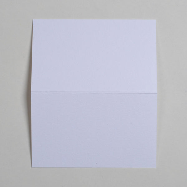 The Bright White Wedding name place cards shown flat on a table surface with the crease in the middle