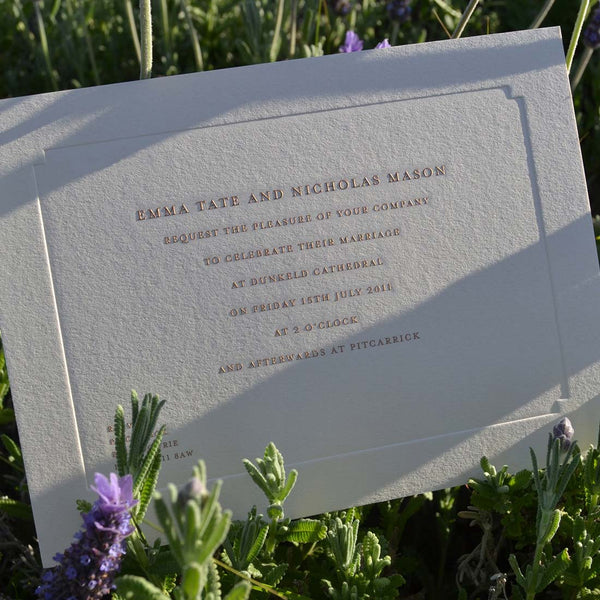 The engraved Hampton Wedding invitation, showing the dazzling sunlight shining off the gold text 