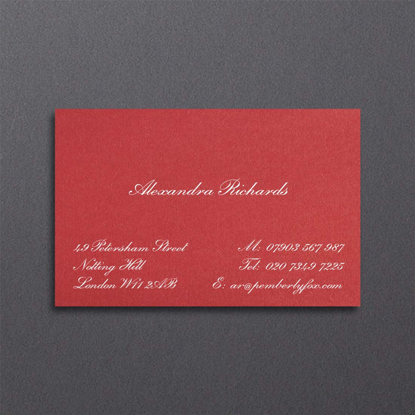 A classic script font printed in white ink onto a bright red visiting card
