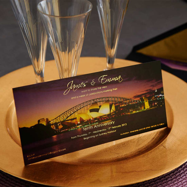 The Sydney Party invitations are foiled in gold ink onto a printed photo of the harbour resting against champagne flutes