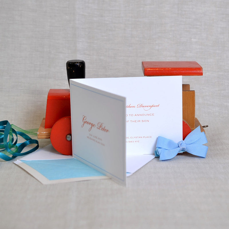 The Torville birth announcement cards on their tissue paper lined envelope and bright orange text