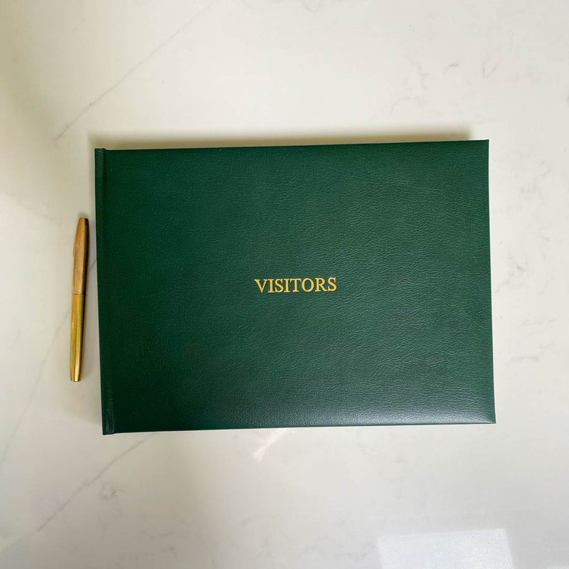 A dark green leather bound visitors book with gold embossing on the front cover