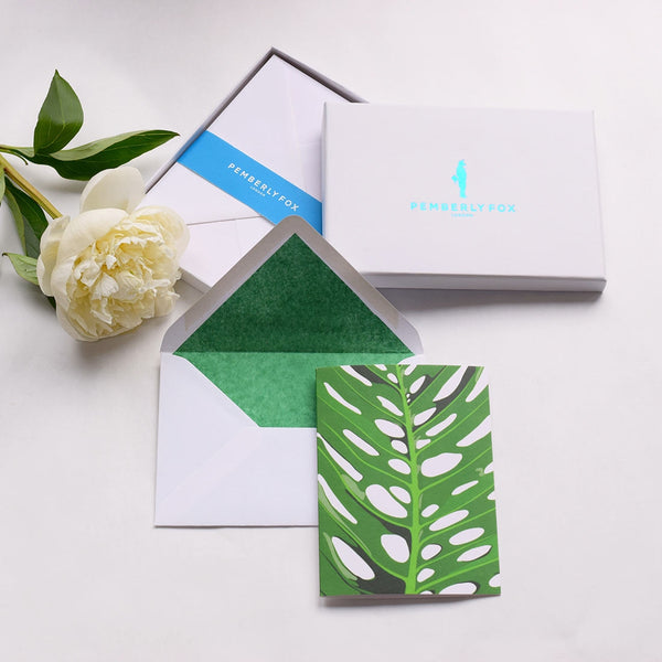 the moon valley greeting cards shows the a Monstera deliciosa leaf with green tissue lined white envelopes