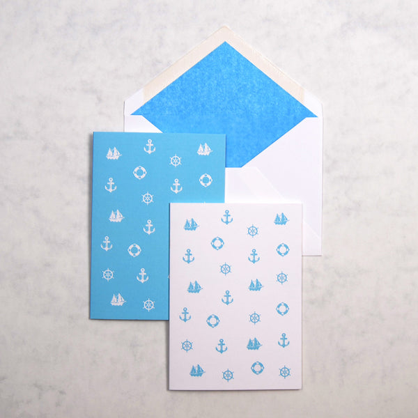 the light blue and white Nice nautical greeting cards show 3 nautical motifs as a pattern on portrait cards, with matching blue tissue paper lined white envelopes