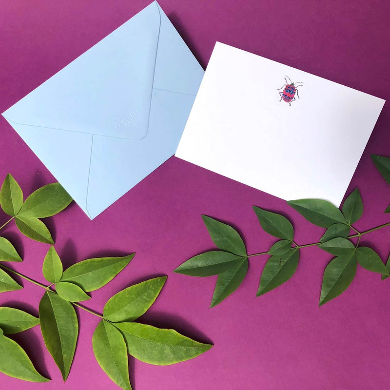The red bug note card shows a single motif sketch at the head and comes with an azure blue envelope 